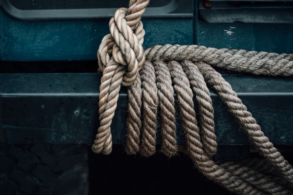 Two thick nautical ropes are coiled around a navy blue metal beam.